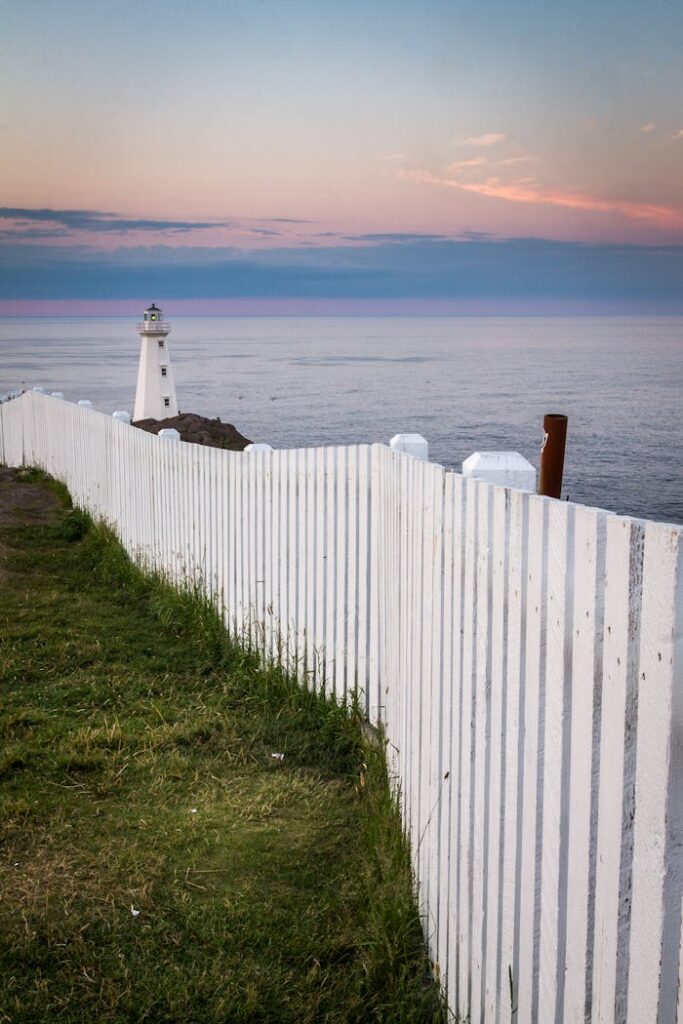 zipwp-image-6124241 Lighthouse placed on seacoast behind fence